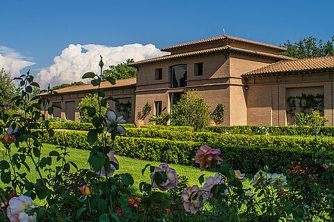 Garten und Haus des Weinguts Tenuta San Guido bei blauem Himmel