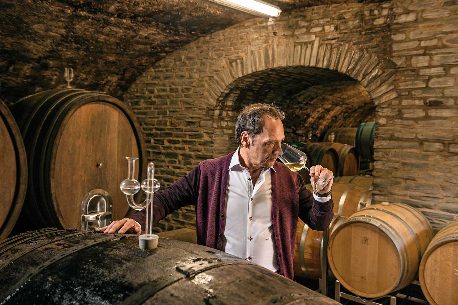Markus Molitor probiert Prädikatsweine im Weinkeller, Weinfässer im Hintergrund