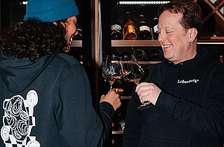 Zwei Personen stoßen mit Wein an