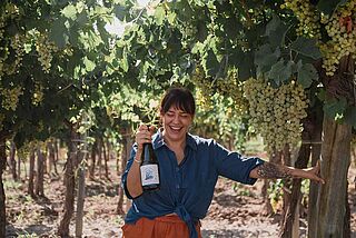 Winzerin mit einer Flasche in der Hand auf dem Weingut Finca Feliz