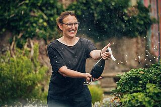 Winzerin Caroline Diel oeffnet eine Schaumweinflasche auf dem Weingut Schlossgut Diel Winzerin Caroline Diel oeffnet eine Schaumweinflasche auf dem Weingut Schlossgut Diel