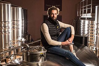 Auf einem Fass sitzender Winzer im Weinkeller Haut Bergey