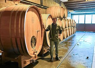 Der Winzer posiert vor seinen Weinfässern