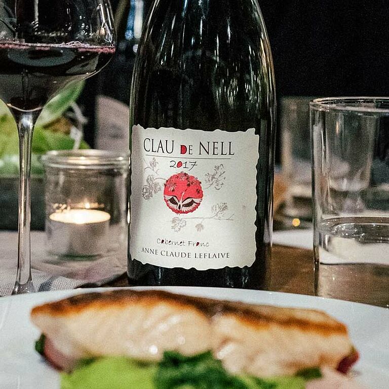Rotwein auf einem Gedeckten Tisch hinter einem Teller mit Fisch