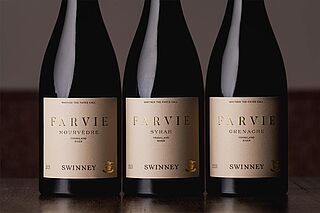 Drei Weinflaschen auf einem Tisch für eine Weinverkostung Rotweinauswahl auf einem Tisch