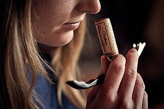 Winzerin riecht an Korken