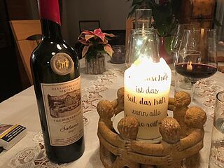 Vinflaske på et dækket bord ved siden af et stearinlys