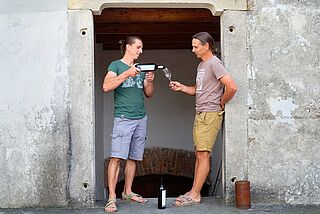 Winzer stehen in der Tür zum Weinkeller Ernst Triebaumer und verkosten Rotwein