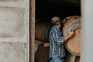 Der Winzer hebt ein Weinfass hoch