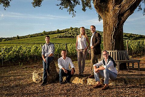 Winzerfamilie vor dem Weingut Monteverro, Baum, blauer Himmel
