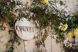 Schild des Weinguts Coutet vor einer Wand mit Blumen