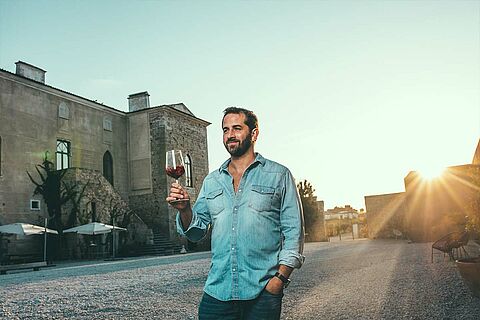 Antonio Macanita mit Rotweinglas vor dem Weingut
