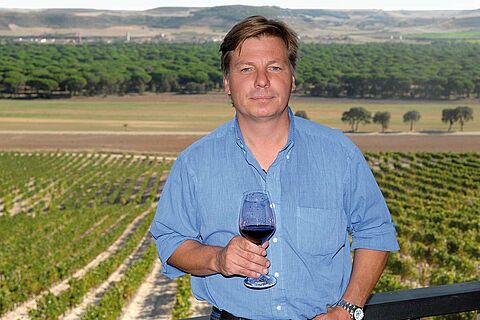 Peter Sisseck mit Weinglas vor dem Weinfeld