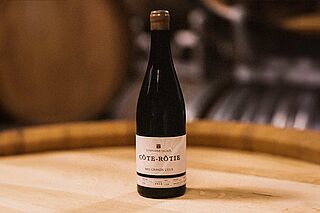 Weinflasche auf einem Weinfass der Domaine Stéphane Ogier