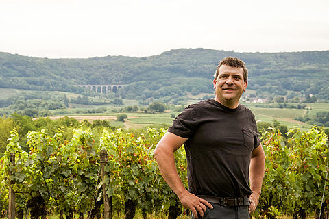 Winzer auf dem Weingut Jerome Arnoux, Weinberge im Hintergrund 