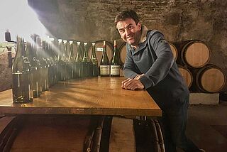 Nicolas Potel im Weinkeller mit Weinflaschen und Weinfässern