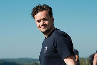 Winzer:in Patrick Jacklin mit Weingut Heitlinger im Hintergrund Winzer:in Patrick Jacklin mit Weingut Heitlinger im Hintergrund