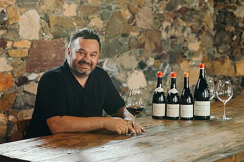 Winzer sitzt an einem Tisch mit Wein