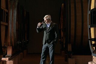 Winzer steht im Weinkeller und riecht an Wein